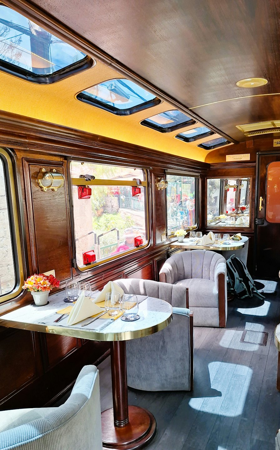 Eleganter Speisewagen eines Zuges mit Marmortischen und Plüschstühlen.