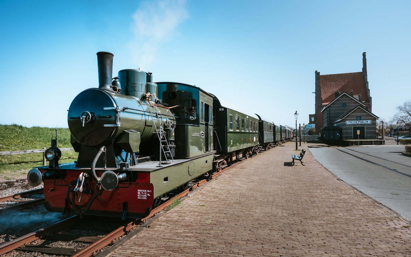 Eine grüne Dampflokomotive wartet auf einem Bahnsteig aus Ziegeln.